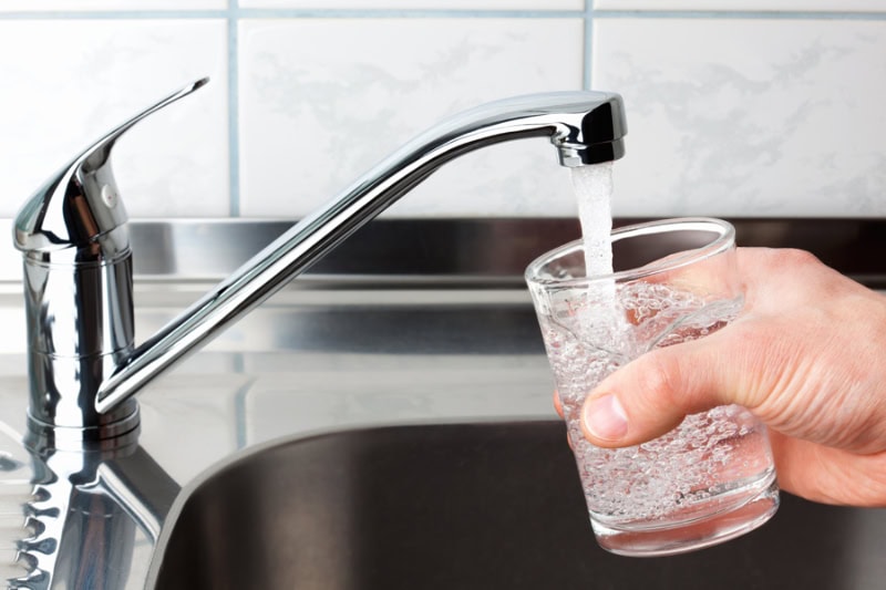 Homeowner filling up a glass of water at the kitchen sink in Poway, California, home.