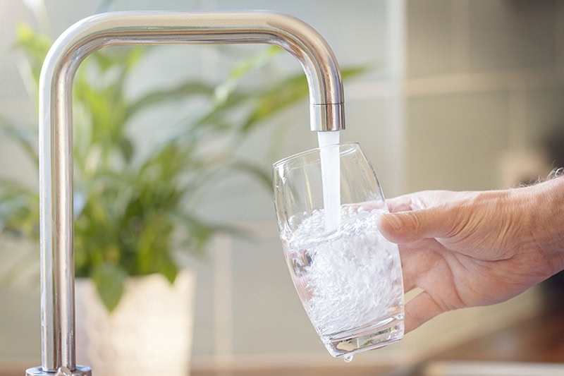 Homeowner filling up glass with faucet.